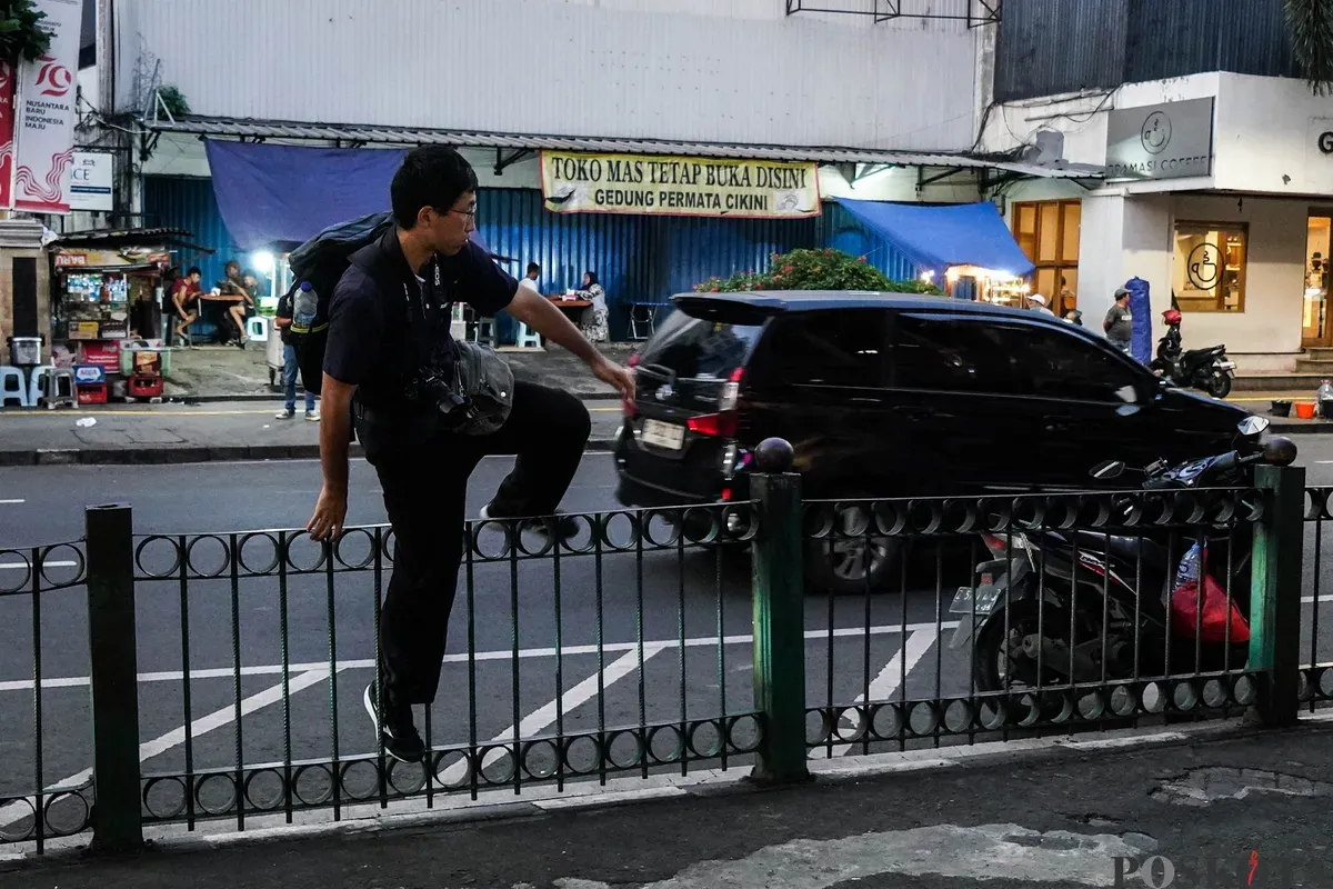 Sejumlah calon penumpang kereta api rela melompati pagar pembatas di depan Stasiun Cikini, Jakarta, Minggu, 4 Mei 2025. (Sumber: Poskota/Bilal Nugraha Ginanjar)