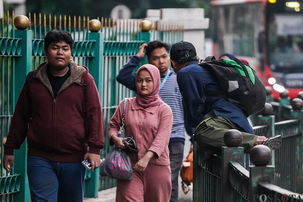 Sejumlah calon penumpang kereta api rela melompati pagar pembatas di depan Stasiun Cikini, Jakarta, Minggu, 4 Mei 2025. (Sumber: Poskota/Bilal Nugraha Ginanjar)