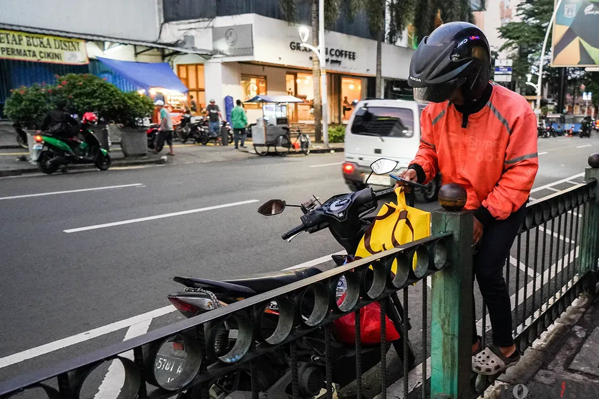 Sejumlah calon penumpang kereta api rela melompati pagar pembatas di depan Stasiun Cikini, Jakarta, Minggu, 4 Mei 2025. (Sumber: Poskota/Bilal Nugraha Ginanjar)