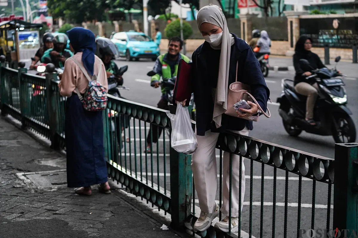 Sejumlah calon penumpang kereta api rela melompati pagar pembatas di depan Stasiun Cikini, Jakarta, Minggu, 4 Mei 2025. (Sumber: Poskota/Bilal Nugraha Ginanjar)