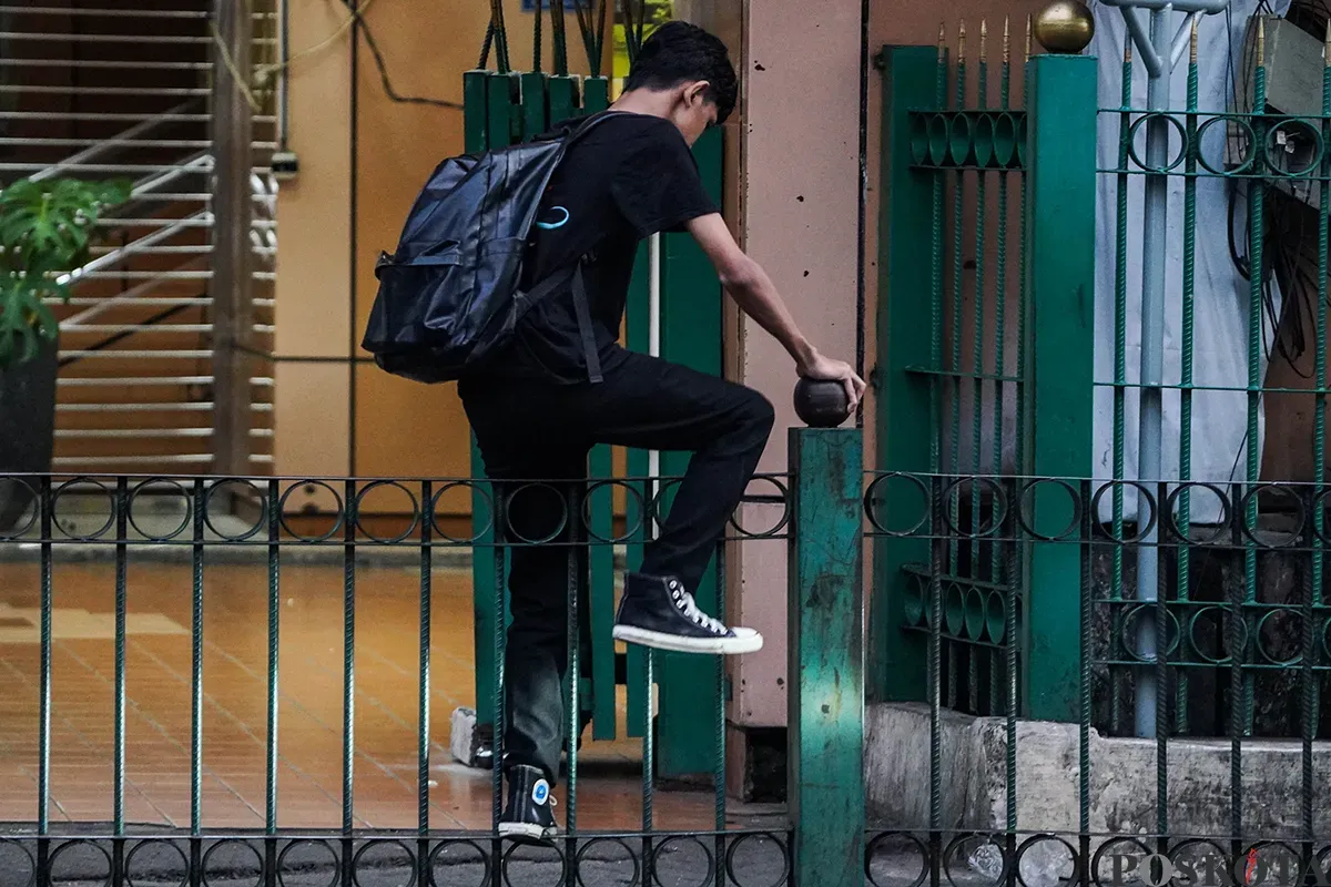 Sejumlah calon penumpang kereta api rela melompati pagar pembatas di depan Stasiun Cikini, Jakarta, Minggu, 4 Mei 2025. (Sumber: Poskota/Bilal Nugraha Ginanjar)