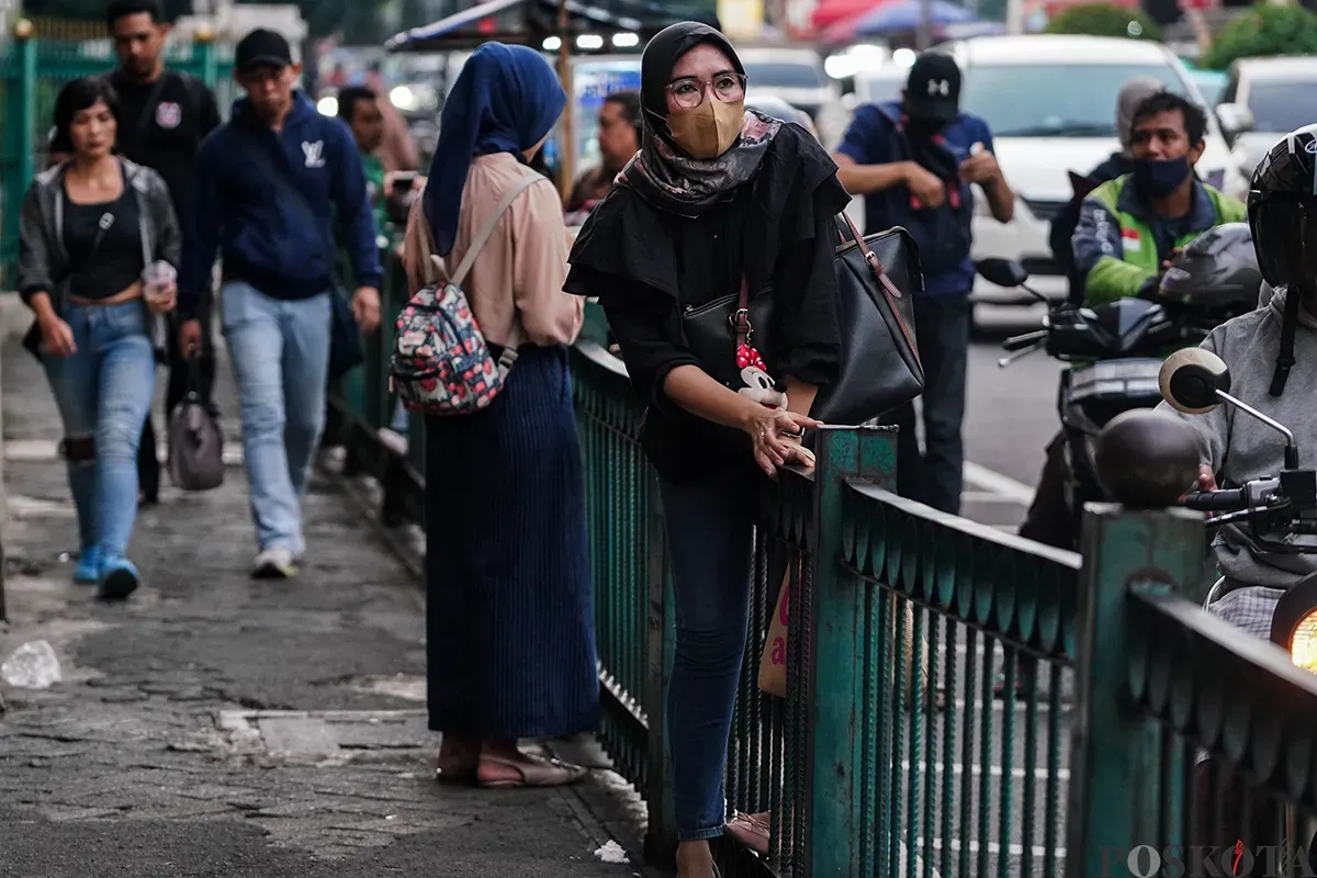Sejumlah calon penumpang kereta api rela melompati pagar pembatas di depan Stasiun Cikini, Jakarta, Minggu, 4 Mei 2025. (Sumber: Poskota/Bilal Nugraha Ginanjar)