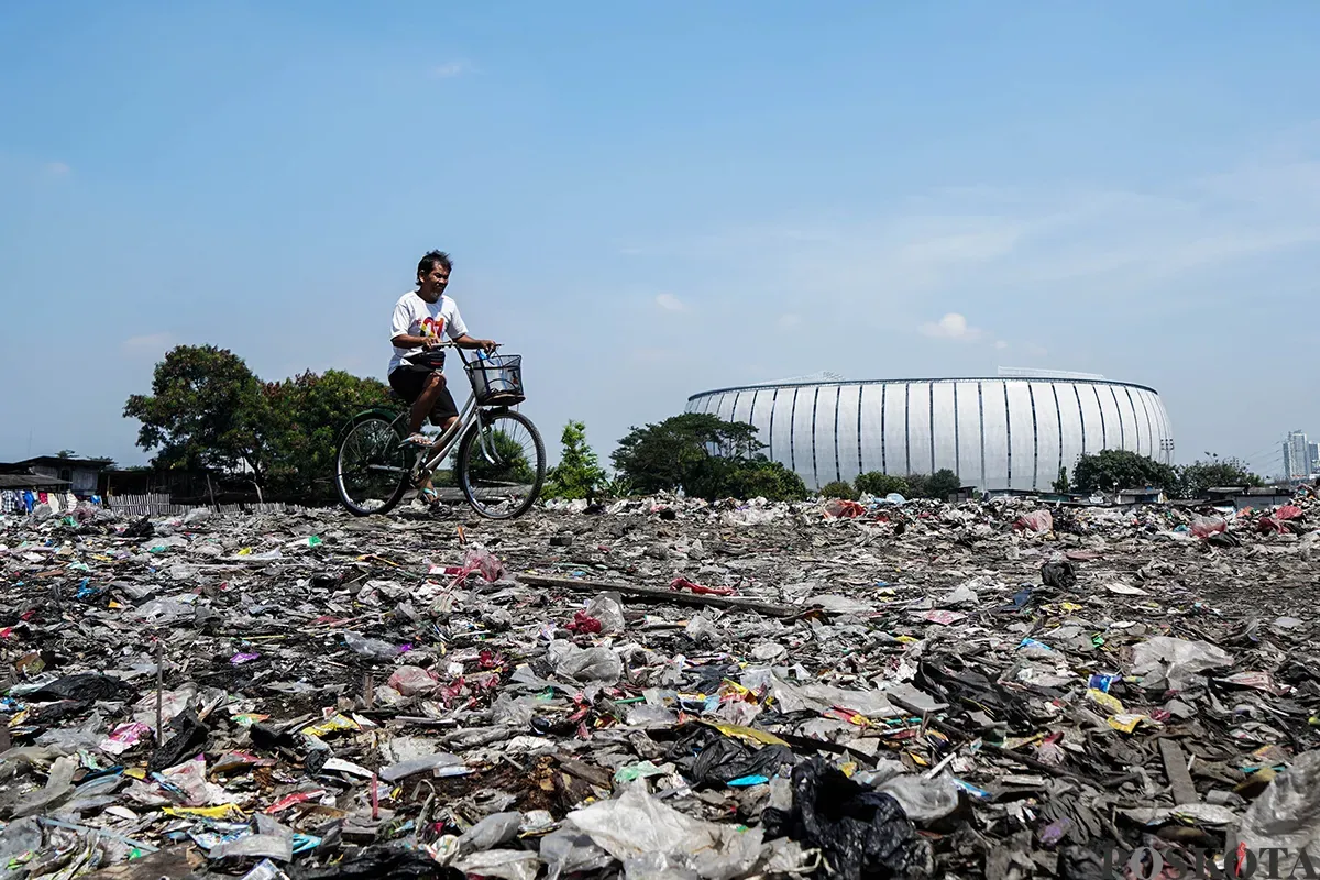 Warga beraktivitas di antara tumpukan sampah yang berada di area kolong jalan tol dalam kota, Kelurahan Papanggo, Jakarta Utara, Senin, 5 Mei 2025. (Sumber: Poskota/Bilal Nugraha Ginanjar)