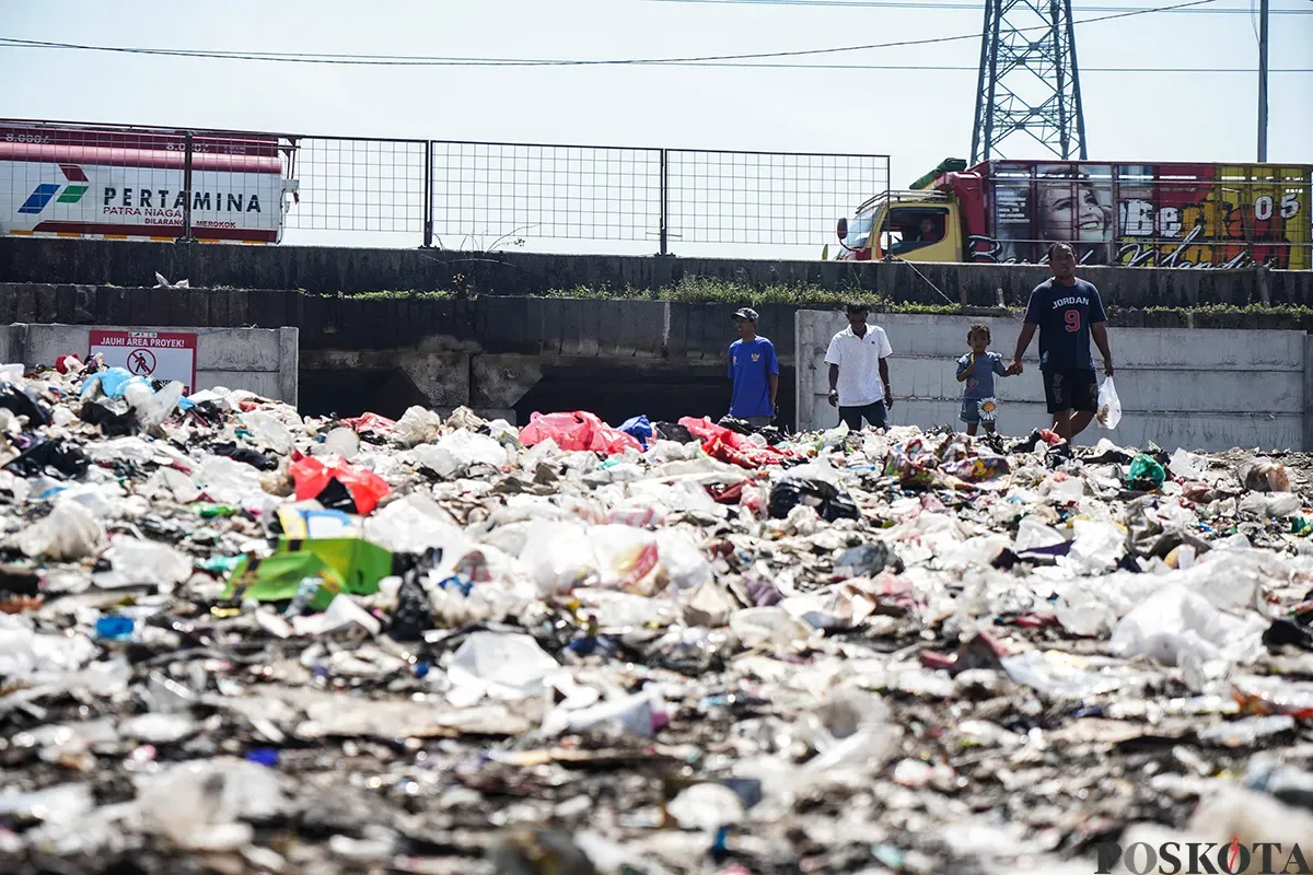 Warga beraktivitas di antara tumpukan sampah yang berada di area kolong jalan tol dalam kota, Kelurahan Papanggo, Jakarta Utara, Senin, 5 Mei 2025. (Sumber: Poskota/Bilal Nugraha Ginanjar)