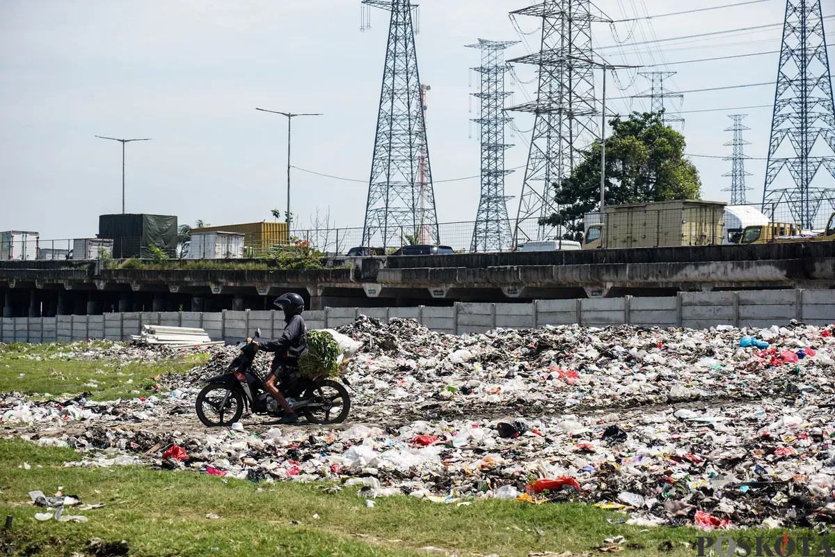 Warga beraktivitas di antara tumpukan sampah yang berada di area kolong jalan tol dalam kota, Kelurahan Papanggo, Jakarta Utara, Senin, 5 Mei 2025. (Sumber: Poskota/Bilal Nugraha Ginanjar)
