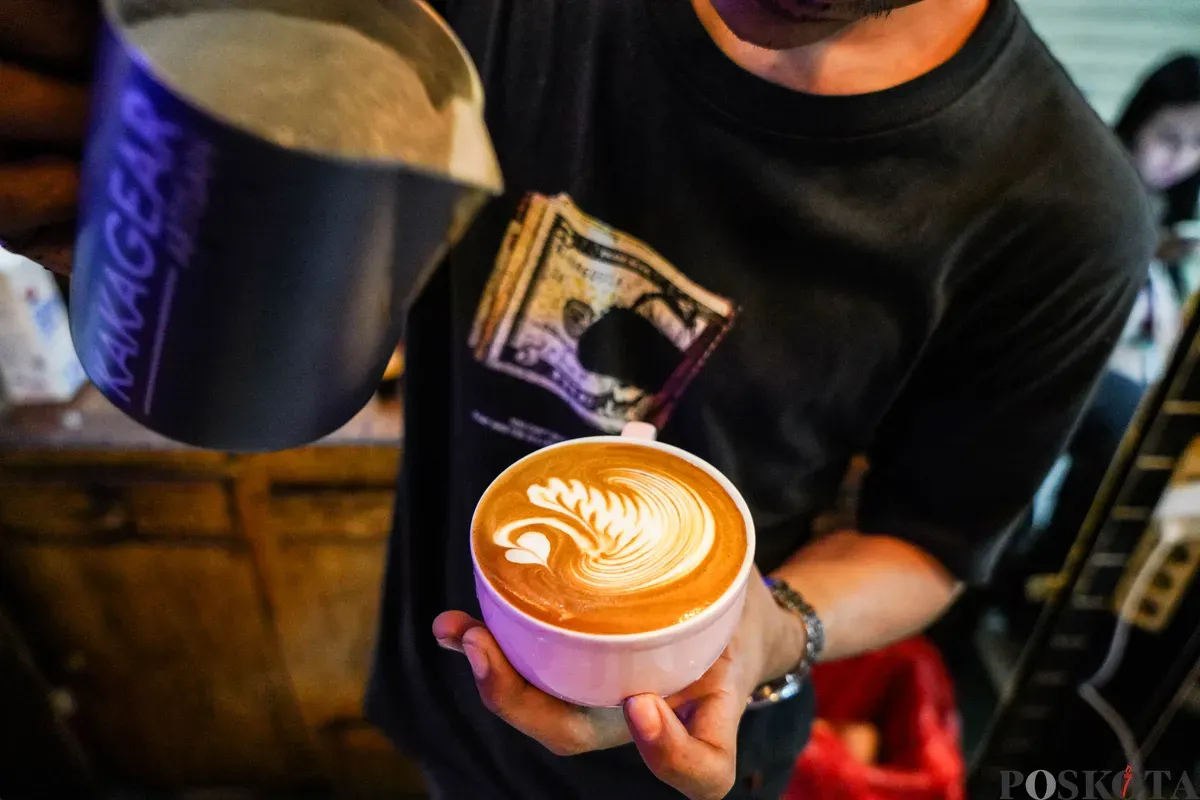 Barista menunjukkan secangkir latte art--seni menghias permukaan segelas kopi susu, di Toko Dunia Kopi, Pasar Santa, Jakarta Selatan, Selasa, 6 Mei 2025. (Sumber: Poskota/Bilal Ginanjar)