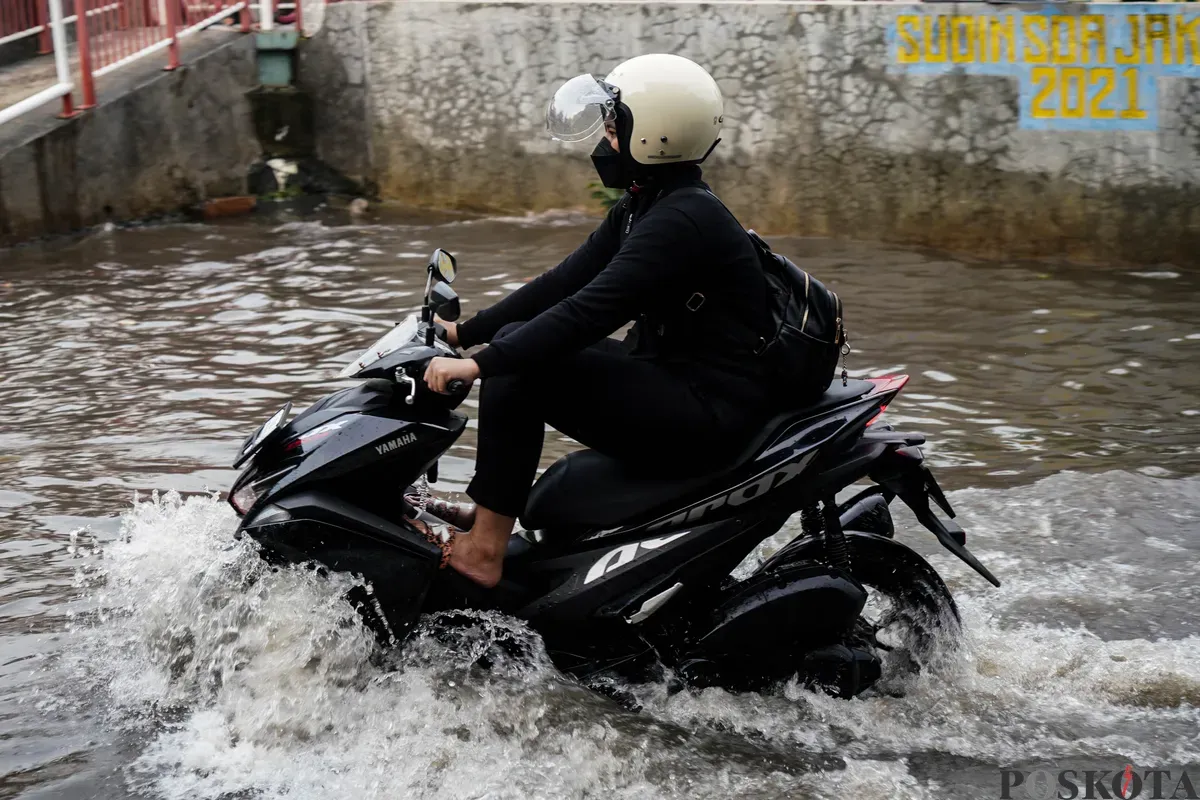 Pengendara motor melintasi genangan banjir di Jalan Pondok Karya, Jakarta Selatan, Rabu, 7 Mei 2025. (Sumber: Poskota/Bilal Nugraha Ginanjar)