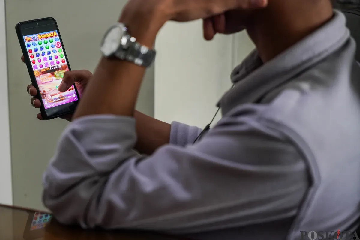 Seorang warga bermain judi online di kawasan perkantoran Palmerah, Jakarta Barat, Jum'at, 9 Mei 2025. (Sumber: Poskota/Bilal Nugraha Ginanjar)
