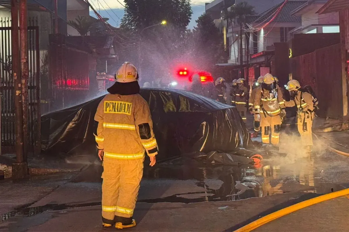 Petugas memadamkan api yang membakar mobil listrik milik warga di Palmerah, Jakarta Barat, Selasa, 13 Mei 2025. (Sumber: Dok. Damkar Jakarta Barat)