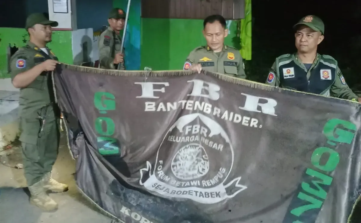 Petugas menurunkan atribut bendera ormas di wilayah Kecamatan Sawangan dan Kecamatan Bojongsari, Selasa dini hari, 20 Mei 2025. (Sumber: Dok. Polsek Bojongsari)