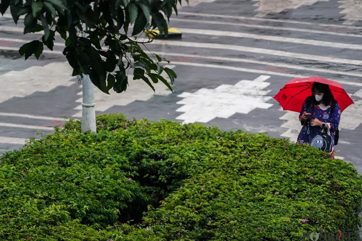 Warga berjalan dengan menggunakan payung di trotoar Jalan Sudirman, Jakarta, Rabu, 21 Mei 2025. (Sumber: Poskota/Bilal Nugraha Ginanjar)