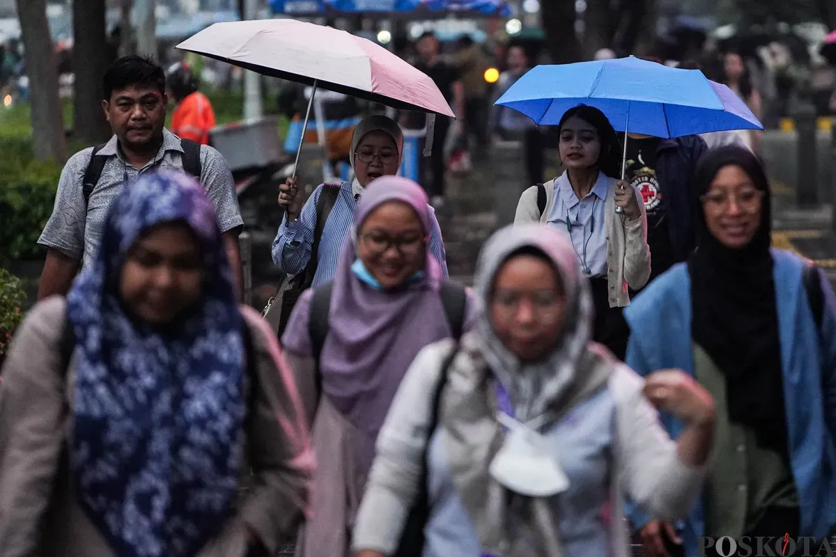 Warga berjalan dengan menggunakan payung di trotoar Jalan Sudirman, Jakarta, Rabu, 21 Mei 2025. (Sumber: Poskota/Bilal Nugraha Ginanjar)