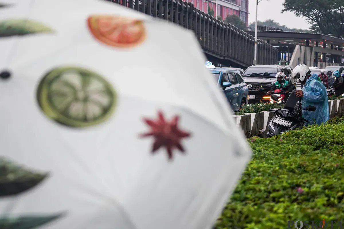 Warga berjalan dengan menggunakan payung di trotoar Jalan Sudirman, Jakarta, Rabu, 21 Mei 2025. (Sumber: Poskota/Bilal Nugraha Ginanjar)