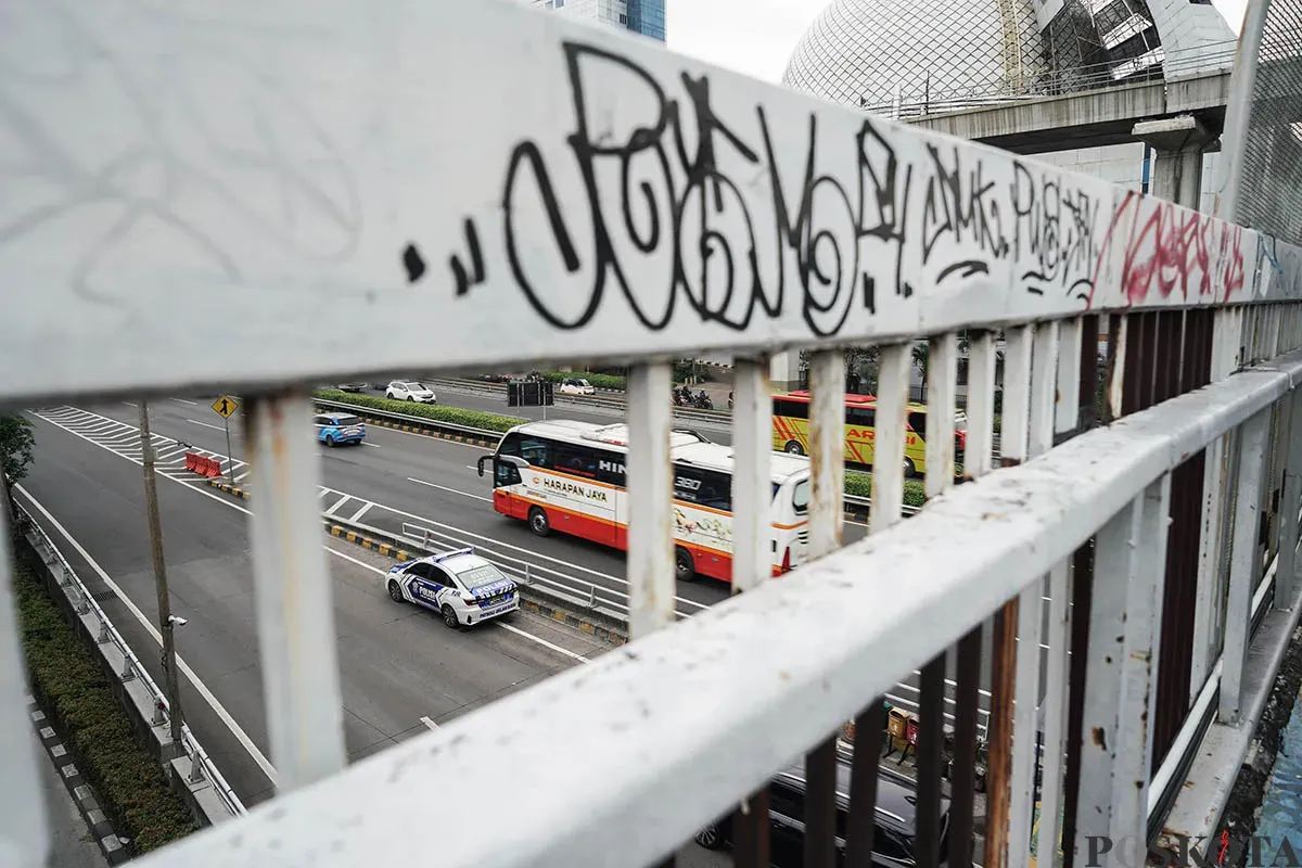 Warga berjalan diatas Jembatan Penyebrangan Orang (JPO) di depan Gedung Smesco, Jalan Gatot Subroto, Jakarta Selatan, tak terawat, Minggu, 25 Mei 2025. (Sumber: Poskota/Bilal Nugraha Ginanjar)