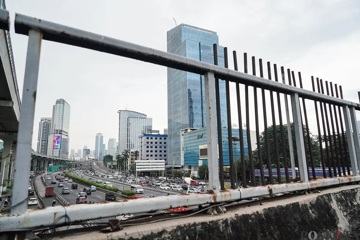 Warga berjalan diatas Jembatan Penyebrangan Orang (JPO) di depan Gedung Smesco, Jalan Gatot Subroto, Jakarta Selatan, tak terawat, Minggu, 25 Mei 2025. (Sumber: Poskota/Bilal Nugraha Ginanjar)