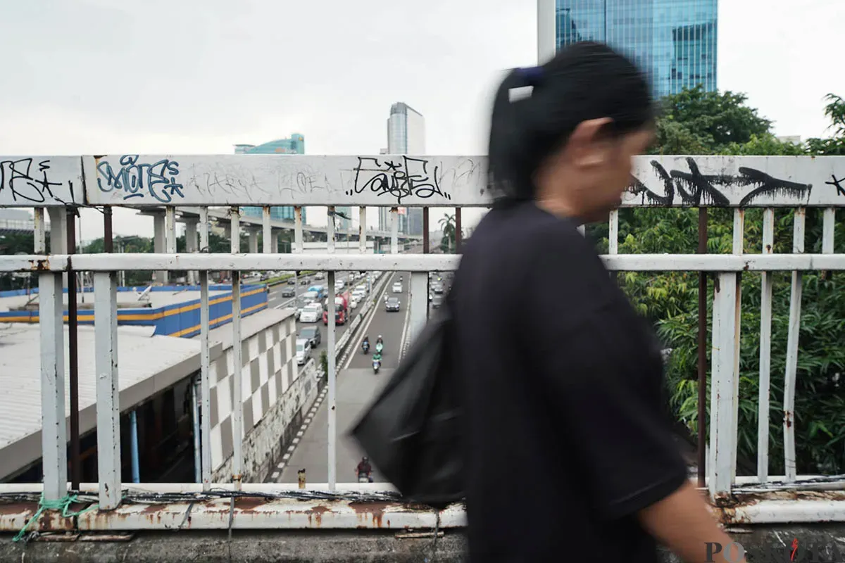 Warga berjalan diatas Jembatan Penyebrangan Orang (JPO) di depan Gedung Smesco, Jalan Gatot Subroto, Jakarta Selatan, tak terawat, Minggu, 25 Mei 2025. (Sumber: Poskota/Bilal Nugraha Ginanjar)