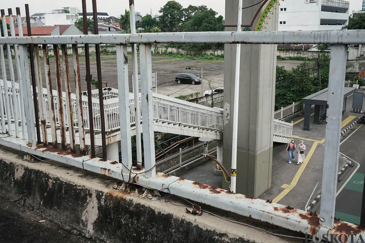 Warga berjalan diatas Jembatan Penyebrangan Orang (JPO) di depan Gedung Smesco, Jalan Gatot Subroto, Jakarta Selatan, tak terawat, Minggu, 25 Mei 2025. (Sumber: Poskota/Bilal Nugraha Ginanjar)