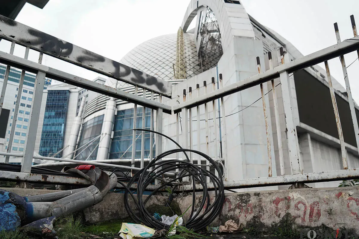 Warga berjalan diatas Jembatan Penyebrangan Orang (JPO) di depan Gedung Smesco, Jalan Gatot Subroto, Jakarta Selatan, tak terawat, Minggu, 25 Mei 2025. (Sumber: Poskota/Bilal Nugraha Ginanjar)
