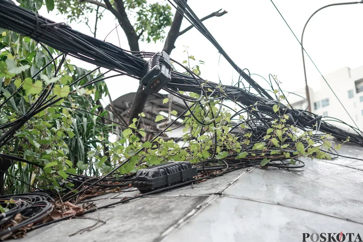 Jaringan kabel utilitas yang menjuntai semrawut di jalur pedestrian kawasan Otista Raya, Jakarta Timur, Minggu, 1 November 2025. (Sumber: Poskota/Bilal Nugraha Ginanjar)