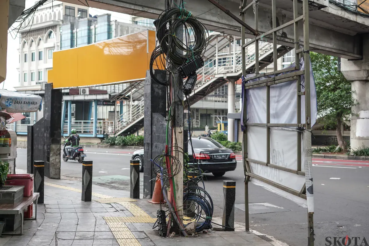 Jaringan kabel utilitas yang menjuntai semrawut di jalur pedestrian kawasan Otista Raya, Jakarta Timur, Minggu, 1 November 2025. (Sumber: Poskota/Bilal Nugraha Ginanjar)