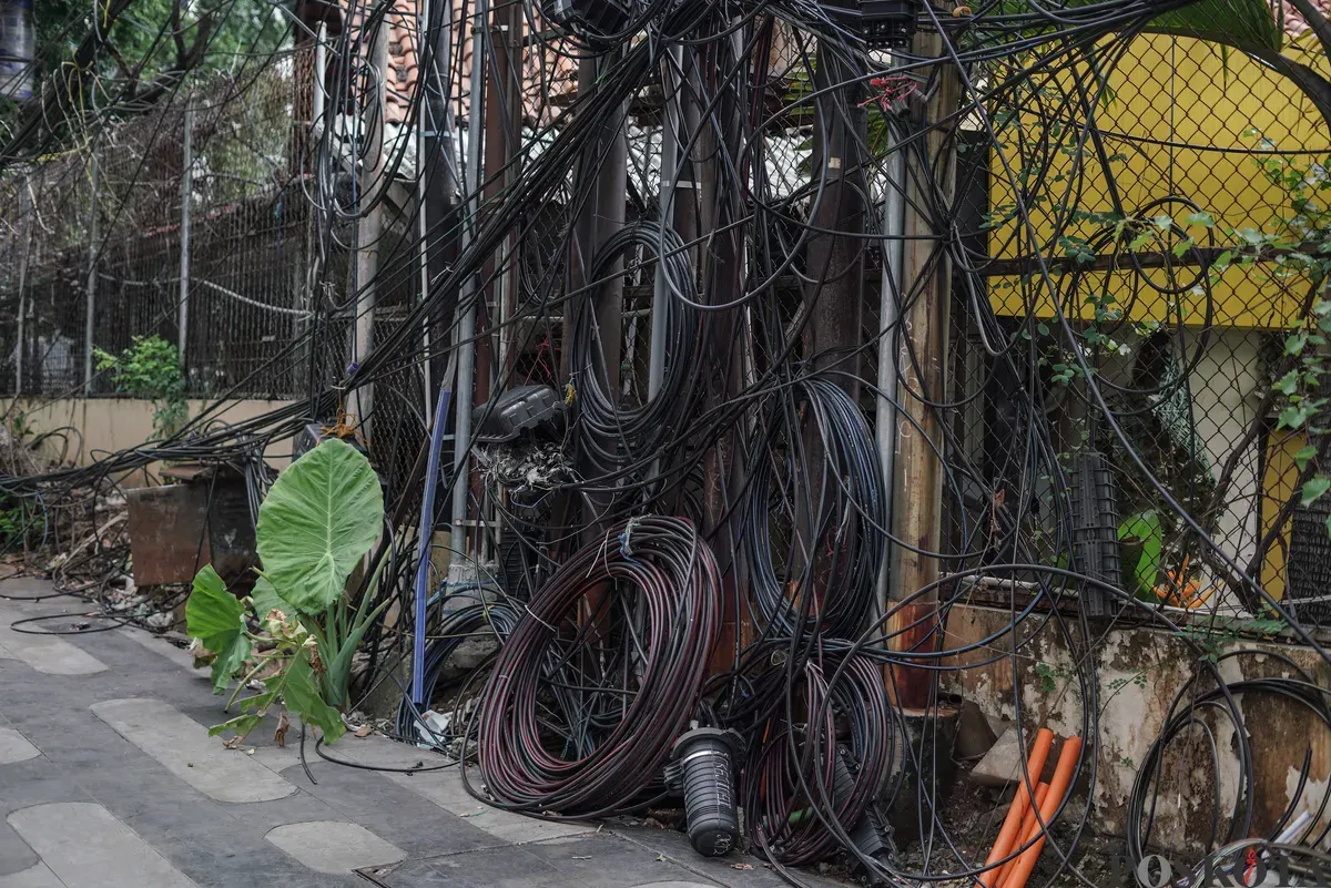 Jaringan kabel utilitas yang menjuntai semrawut di jalur pedestrian kawasan Otista Raya, Jakarta Timur, Minggu, 1 November 2025. (Sumber: Poskota/Bilal Nugraha Ginanjar)
