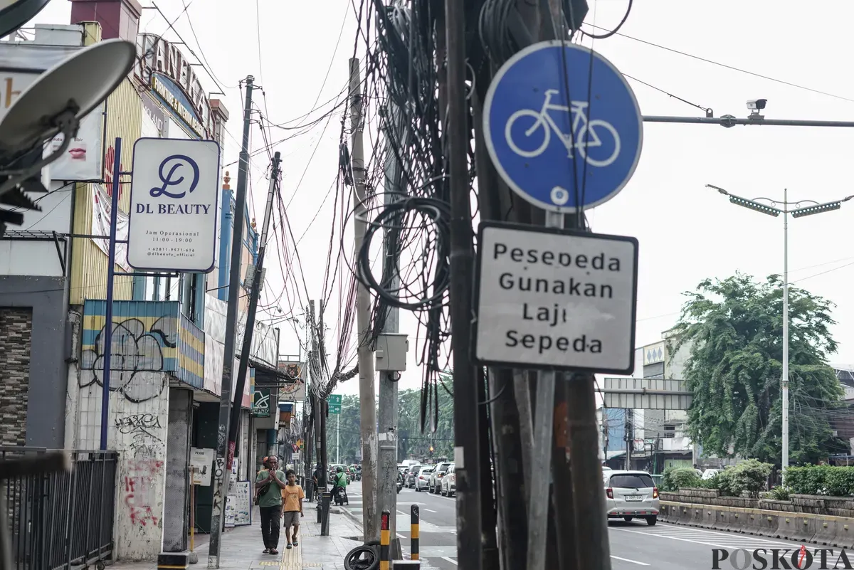 Jaringan kabel utilitas yang menjuntai semrawut di jalur pedestrian kawasan Otista Raya, Jakarta Timur, Minggu, 1 November 2025. (Sumber: Poskota/Bilal Nugraha Ginanjar)