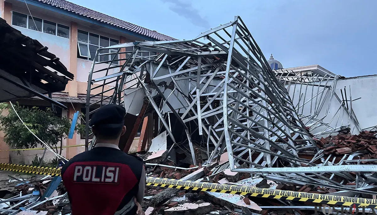 Petugas polisi berjaga di SMKN 1 Gunung Putri yang ambruk akibat hujan deras dan angin kencang yang melanda wilayah tersebut. (Sumber: POSKOTA | Foto: Giffar Rivana)