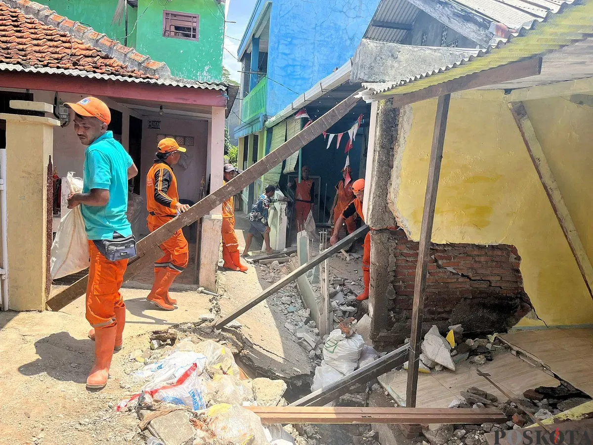 Petugas PPSU membantu membersihkan bangunan warga yang rusak akibat tanah amblas di GG Sumur Jambu, Kelurahan/Kecamatan Makasar, Jaktim. (Sumber: POSKOTA | Foto: M Tegar Jihad)