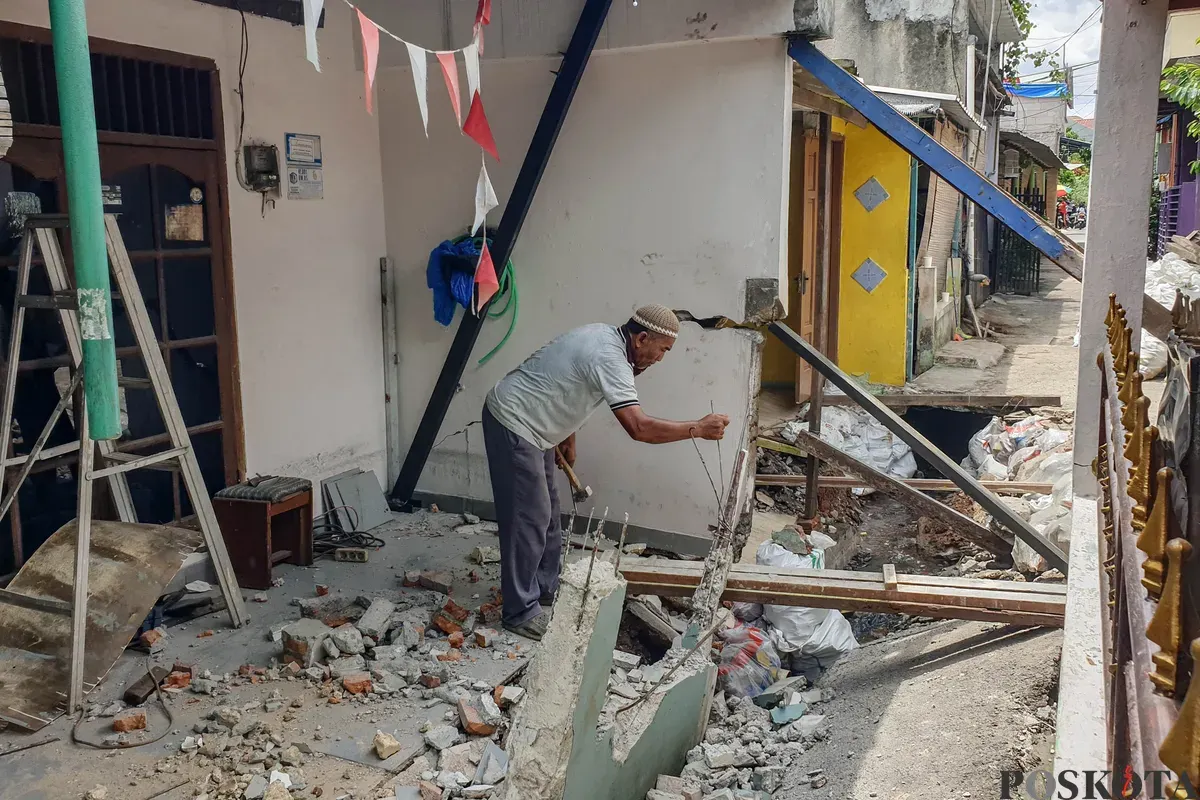 Warga membersihkan puing - puing rumahnya yang hancur akibat pergerakan tanah di Gang Sumur Jambu, Makasar, Jakarta Timur. (Sumber: Poskota/Bilal Nugraha Ginanjar)