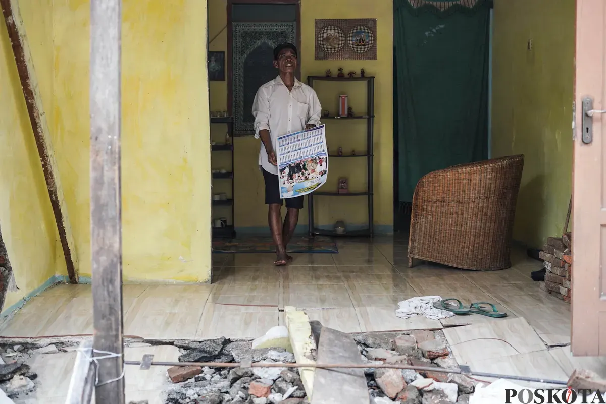 Warga membersihkan puing - puing rumahnya yang hancur akibat pergerakan tanah di Gang Sumur Jambu, Makasar, Jakarta Timur. (Sumber: Poskota/Bilal Nugraha Ginanjar)