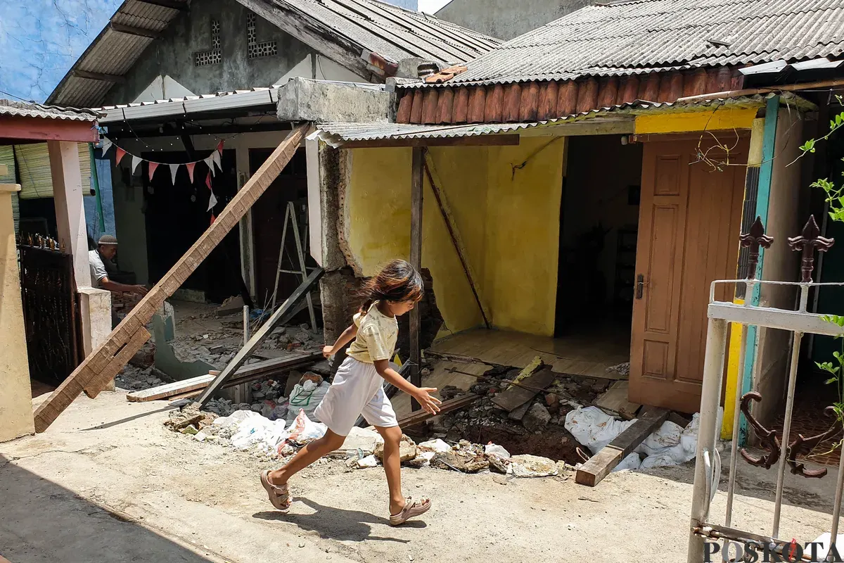 Warga membersihkan puing - puing rumahnya yang hancur akibat pergerakan tanah di Gang Sumur Jambu, Makasar, Jakarta Timur. (Sumber: Poskota/Bilal Nugraha Ginanjar)
