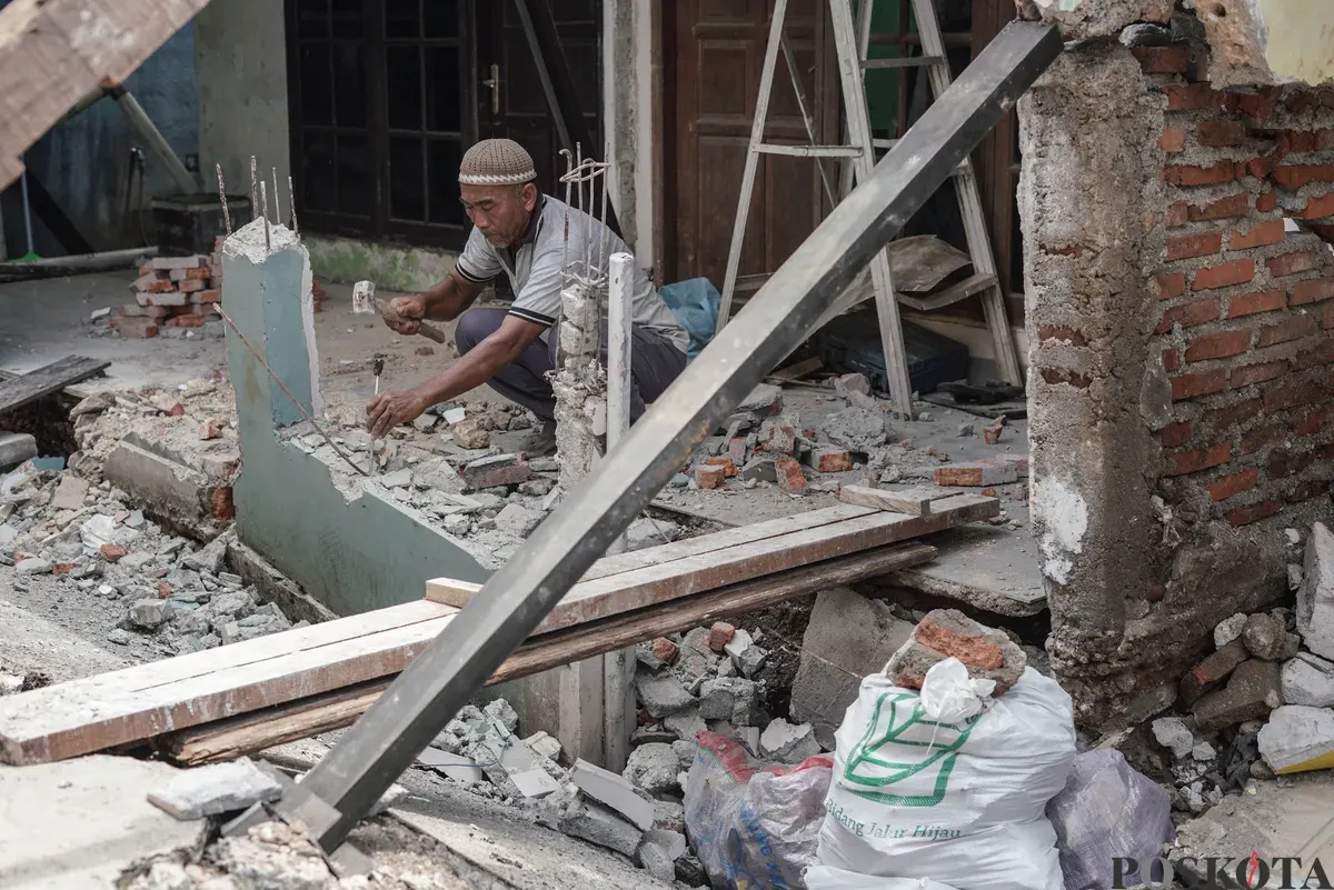 Warga membersihkan puing - puing rumahnya yang hancur akibat pergerakan tanah di Gang Sumur Jambu, Makasar, Jakarta Timur. (Sumber: Poskota/Bilal Nugraha Ginanjar)