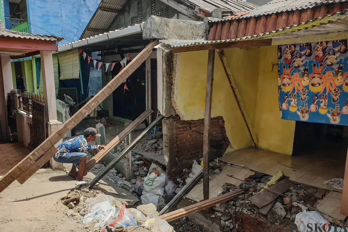 Warga membersihkan puing - puing rumahnya yang hancur akibat pergerakan tanah di Gang Sumur Jambu, Makasar, Jakarta Timur. (Sumber: Poskota/Bilal Nugraha Ginanjar)