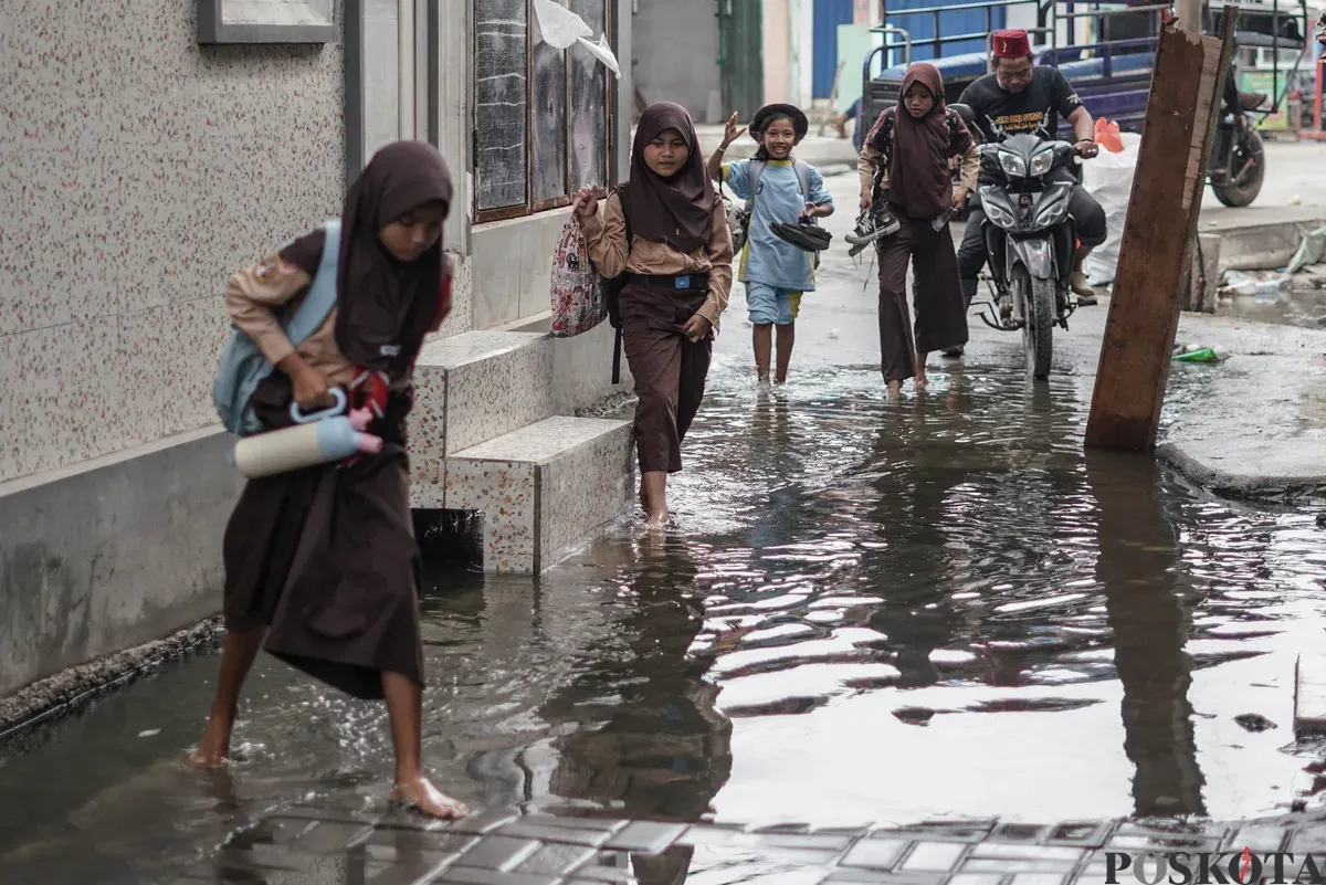 Warga melintasi genangan banjir rob di Muara Angke, Jakarta Utara, Rabu, 5 November 2025. (Sumber: Poskota/Bilal Nugraha Ginanjar)