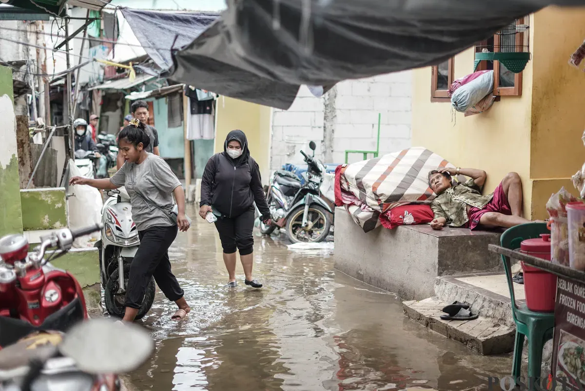 Warga melintasi genangan banjir rob di Muara Angke, Jakarta Utara, Rabu, 5 November 2025. (Sumber: Poskota/Bilal Nugraha Ginanjar)
