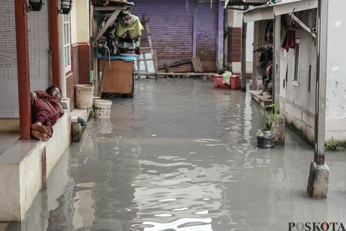 Warga melintasi genangan banjir rob di Muara Angke, Jakarta Utara, Rabu, 5 November 2025. (Sumber: Poskota/Bilal Nugraha Ginanjar)