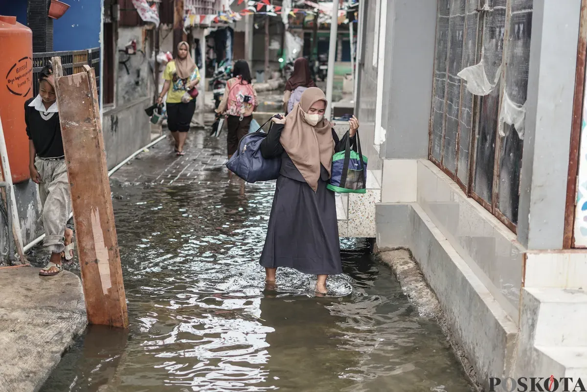 Warga melintasi genangan banjir rob di Muara Angke, Jakarta Utara, Rabu, 5 November 2025. (Sumber: Poskota/Bilal Nugraha Ginanjar)