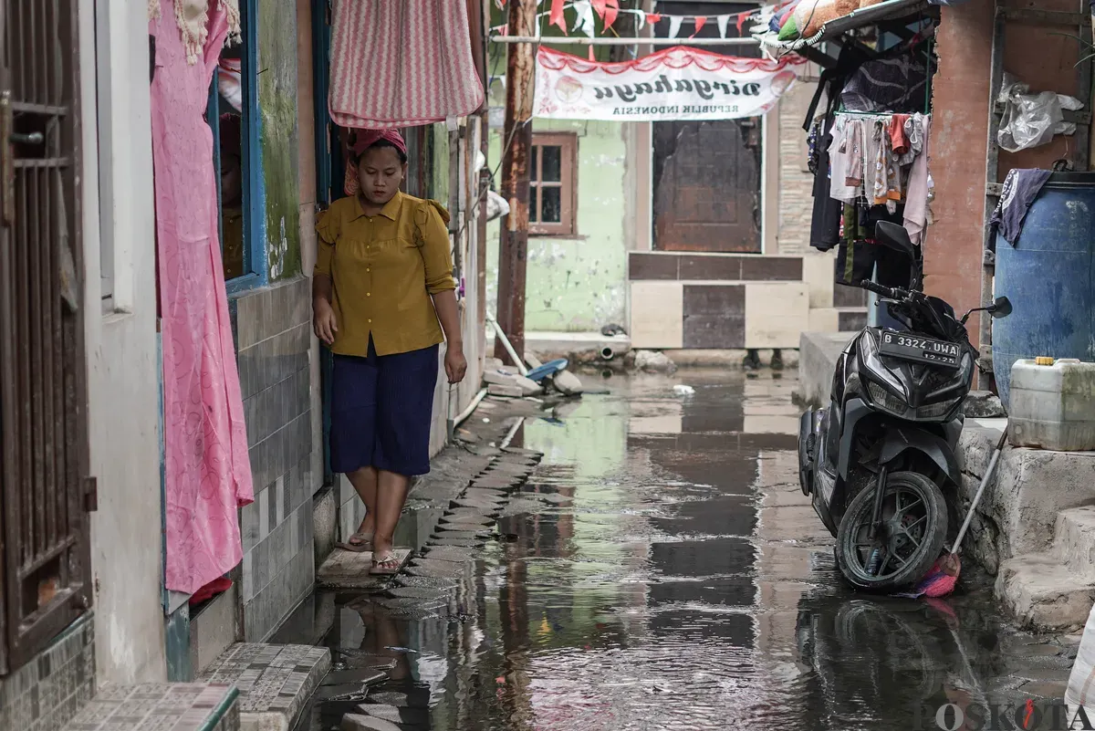 Warga melintasi genangan banjir rob di Muara Angke, Jakarta Utara, Rabu, 5 November 2025. (Sumber: Poskota/Bilal Nugraha Ginanjar)