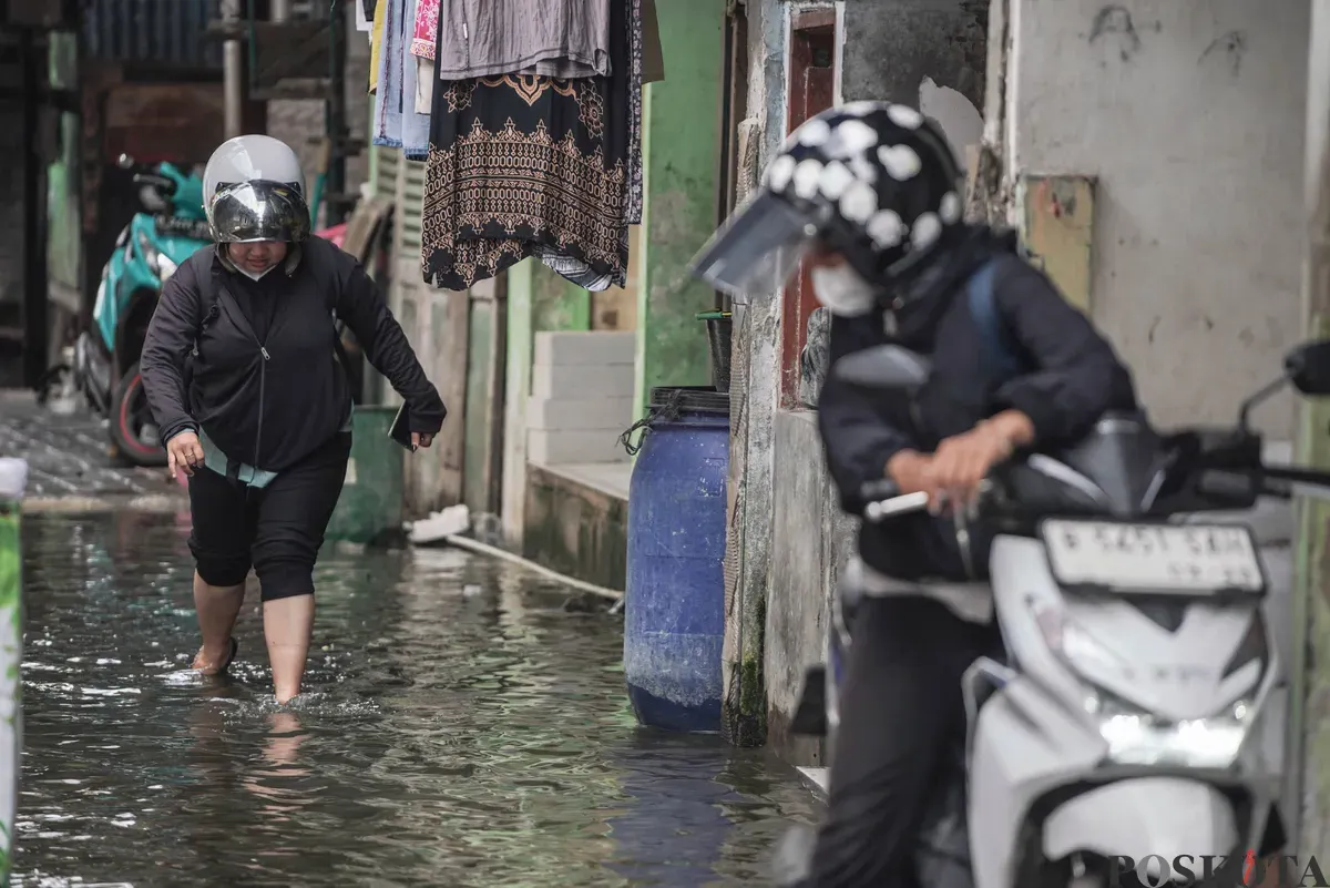 Warga melintasi genangan banjir rob di Muara Angke, Jakarta Utara, Rabu, 5 November 2025. (Sumber: Poskota/Bilal Nugraha Ginanjar)