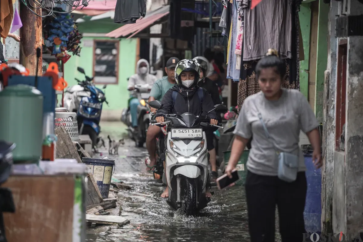 Warga melintasi genangan banjir rob di Muara Angke, Jakarta Utara, Rabu, 5 November 2025. (Sumber: Poskota/Bilal Nugraha Ginanjar)
