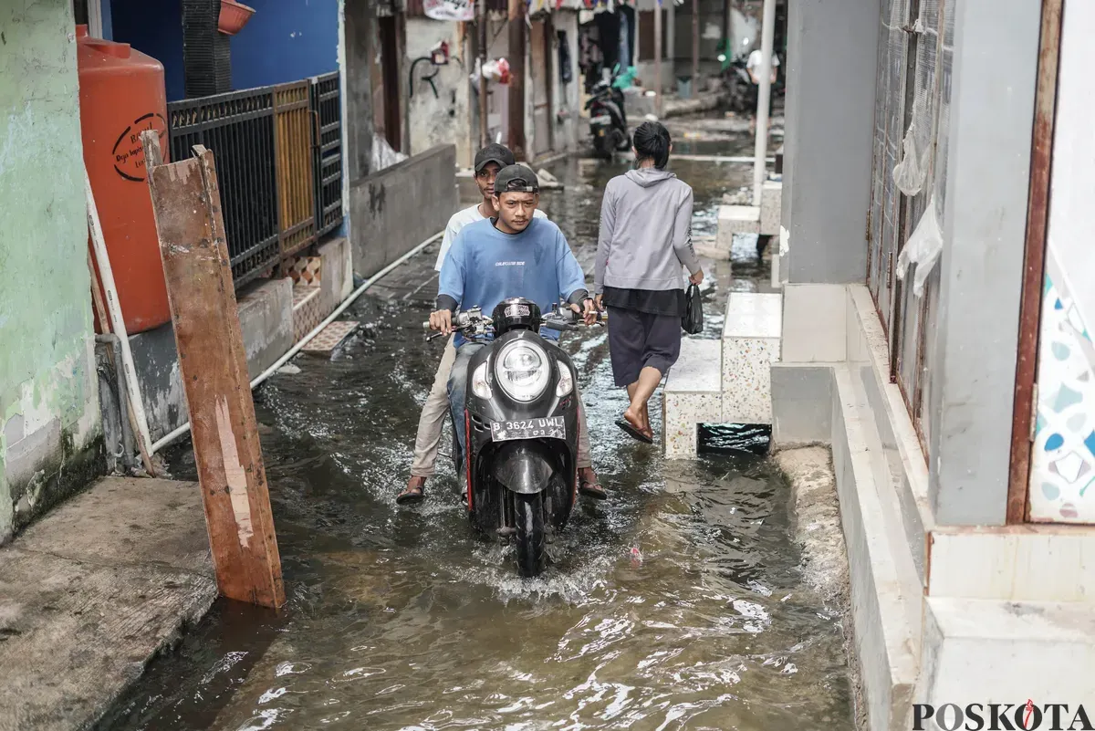 Warga melintasi genangan banjir rob di Muara Angke, Jakarta Utara, Rabu, 5 November 2025. (Sumber: Poskota/Bilal Nugraha Ginanjar)