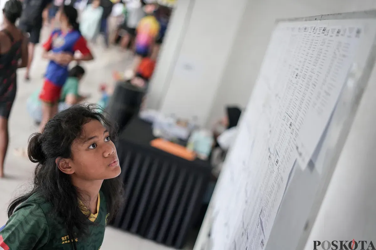 Seorang atlet melihat papan jadwal kejuaraan terbuka akuatik Indonesia 2025 di Stadion Akuatik, Kompleks GBK, Senayan, Jakarta, Rabu, 11 November 2025. (Sumber: Poskota/Bilal Nugraha Ginanjar)
