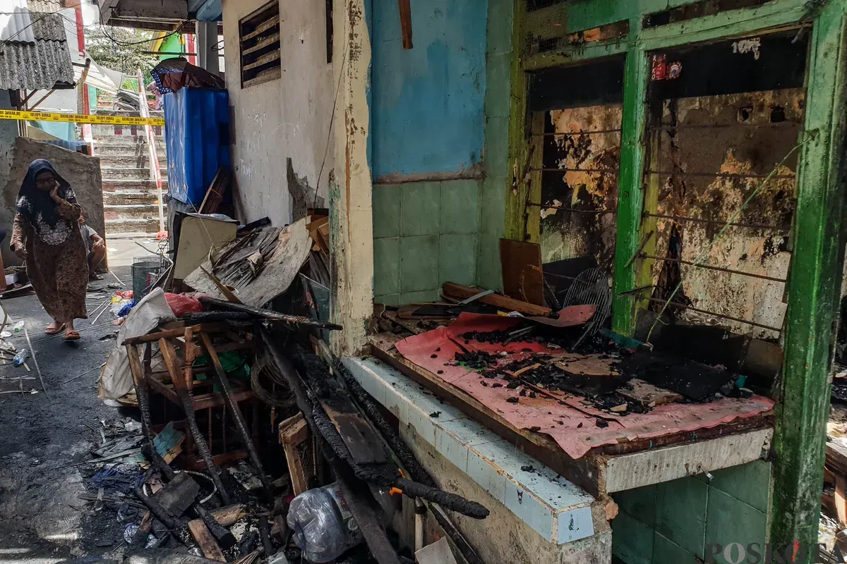 Warga berjalan di sekitar lokasi kebakaran akibat putusnya ground steel wire jaringan saluran udara tegangan tinggi di RW 004 Jatipulo, Jakarta Barat, Senin, 17 November 2025. (Sumber: Poskota/Bilal Nugraha Ginanjar)