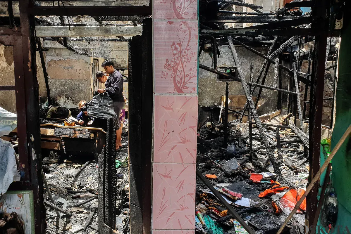 Warga berjalan di sekitar lokasi kebakaran akibat putusnya ground steel wire jaringan saluran udara tegangan tinggi di RW 004 Jatipulo, Jakarta Barat, Senin, 17 November 2025. (Sumber: Poskota/Bilal Nugraha Ginanjar)