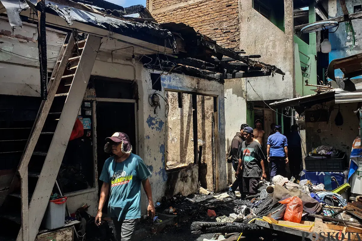 Warga berjalan di sekitar lokasi kebakaran akibat putusnya ground steel wire jaringan saluran udara tegangan tinggi di RW 004 Jatipulo, Jakarta Barat, Senin, 17 November 2025. (Sumber: Poskota/Bilal Nugraha Ginanjar)