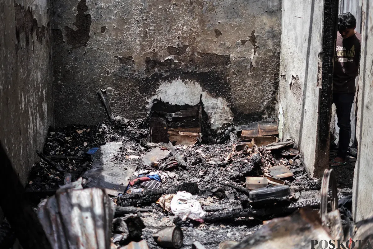 Warga berjalan di sekitar lokasi kebakaran akibat putusnya ground steel wire jaringan saluran udara tegangan tinggi di RW 004 Jatipulo, Jakarta Barat, Senin, 17 November 2025. (Sumber: Poskota/Bilal Nugraha Ginanjar)