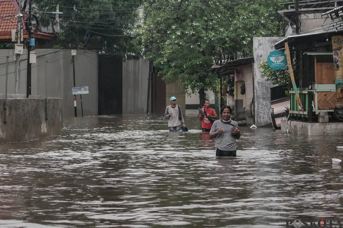 Warga berjalan menerobos banjir di Kompleks Polri Pondok Karya, Mampang Prapatan, Jakarta, Selasa, 18 November 2025. (Sumber: Poskota/Bilal Nugraha Ginanjar)
