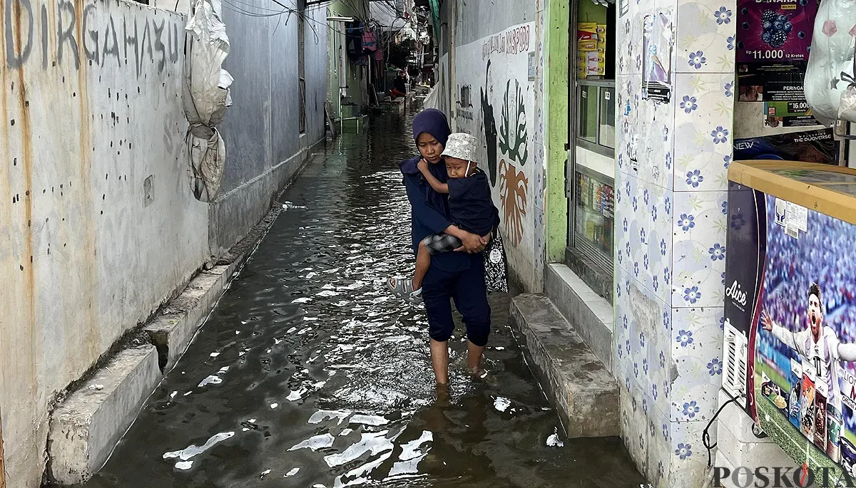 Warga melintasi genangan air akibat banjir rob di RW 22 Kelurahan Muara Angke, Kecamatan Penjaringan, Jakarta Utara pada Sabtu, 22 November 2025. (Sumber: POSKOTA | Foto: Pandi Ramedhan)