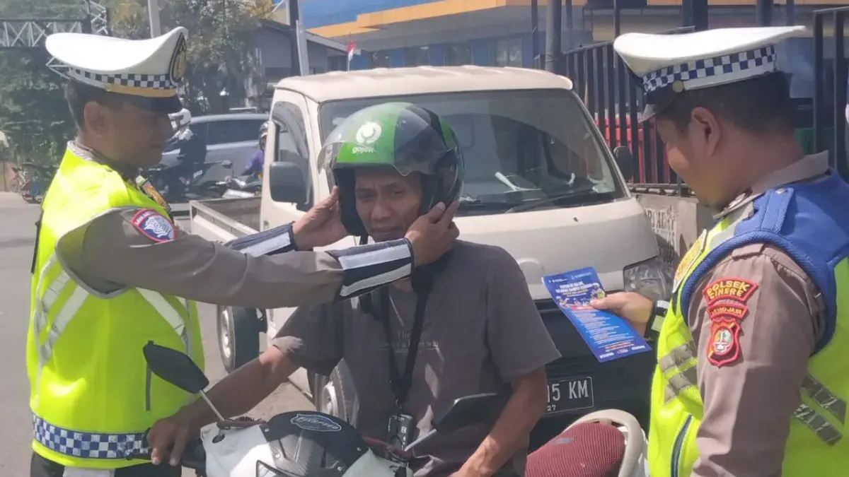 Kanit Lantas Polsek Cinere, Iptu Suharyoko memasangkan helm kepada pengendara saat Operasi Zebra Jaya 2025. (Sumber: Dok. Polsek Cinere)