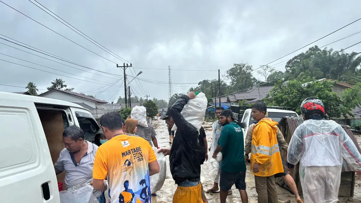 Relawan mendistribusikan paket MBG kepada warga yang terdampak banjir di Tapanuli Selatan meski akses jalan dipenuhi lumpur. (Sumber: Biro Hukum dan Humas BGN)